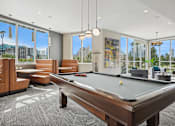 Thumbnail 34 of 40 - A pool table is in the middle of a room with leather chairs and a view of the city.
