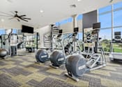 Thumbnail 25 of 40 - A gym with a variety of equipment including treadmills, weights, and exercise machines.