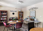 Thumbnail 16 of 24 - a library with a table and chairs and a bookcase filled with books