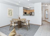 Thumbnail 3 of 24 - a dining area with a table and chairs and a kitchen in the background