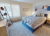 Thumbnail 18 of 28 - A bedroom with a bed, nightstand, and a window with blinds at The Bosk Apartment Homes, Woodbury, MN, 55125