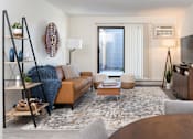 Thumbnail 12 of 28 - a living room with a couch and a table and a tv at The Bosk Apartment Homes, Woodbury, Minnesota