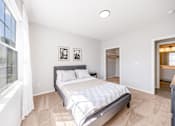 Thumbnail 9 of 30 - A bedroom with a large bed and a window with curtains.