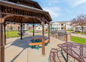Thumbnail 22 of 30 - A patio with a table and chairs under a wooden pergola.