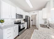 Thumbnail 3 of 30 - A kitchen with white cabinets and a granite countertop.