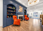 Thumbnail 23 of 30 - A living room with a fireplace and two orange chairs.