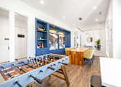 Thumbnail 26 of 30 - A foosball table is in the middle of a room with a blue cabinet and a wooden table.