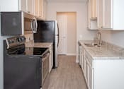 Thumbnail 7 of 30 - Modern kitchen with white cabinetry, stainless steel appliances, and vinyl wood style flooring throughout kitchen into the dining room.