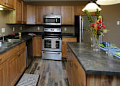 Thumbnail 2 of 10 - a kitchen with wooden cabinets and stainless steel appliances