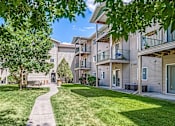 Thumbnail 13 of 18 - a walkway between two apartment buildings with grass and trees