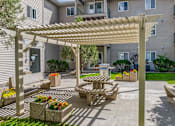 Thumbnail 11 of 18 - a patio with a picnic table and a pergola in front of a building