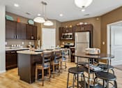 Thumbnail 2 of 27 - A kitchen with brown cabinets and a white island.