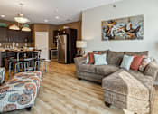 Thumbnail 4 of 27 - A living room with a grey couch and a painting on the wall.