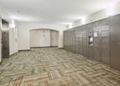 Thumbnail 26 of 27 - A long hallway with a carpeted floor and a wall of lockers on the right.