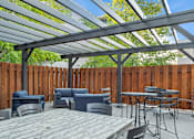 Thumbnail 15 of 27 - A patio with a table and chairs under a roof.