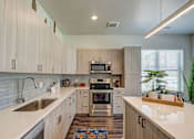 Thumbnail 6 of 40 - A modern kitchen with cabinets, white countertops and kitchen island.