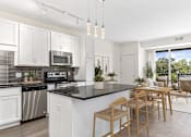 Thumbnail 4 of 31 - A modern kitchen with white cabinets and a black countertop.