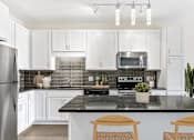 Thumbnail 5 of 31 - A modern kitchen with a black countertop and white cabinets.