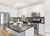 Thumbnail 1 of 31 - A modern kitchen with a black countertop and stainless steel appliances.