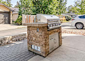 Thumbnail 23 of 31 - A small outdoor kitchen with a grill and sink.