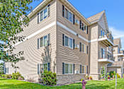 Thumbnail 11 of 14 - an apartment building with tan siding and a sidewalk in front of it