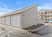 Thumbnail 12 of 14 - a small garage with white doors in front of an apartment building