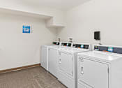 Thumbnail 10 of 14 - a laundry room with four washers and dryers and a table with laundry machines