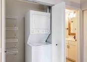 Thumbnail 13 of 16 - Closet with stacked in unit washer and dryer with shelving and storage.