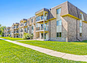 Thumbnail 14 of 18 - an exterior view of an apartment building with green grass and a sidewalk