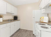 Thumbnail 3 of 18 - a kitchen with white cabinets and appliances and a white refrigerator