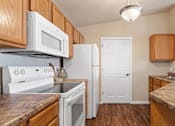 Thumbnail 5 of 24 - a kitchen with white appliances and wooden cabinets