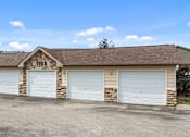 Thumbnail 24 of 24 - a brick garage with white doors and a sign on the roof