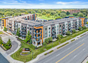 Thumbnail 1 of 36 - A large apartment complex with a green lawn in front.