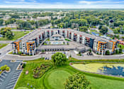 Thumbnail 35 of 36 - A large, multi-story building with a parking lot in front and a pond in the front yard.