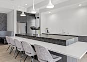 Thumbnail 30 of 36 - A modern kitchen with a marble countertop and grey chairs.