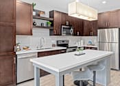 Thumbnail 3 of 36 - A modern kitchen with a white island and brown cabinets.