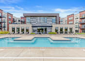 Thumbnail 21 of 36 - A large swimming pool in front of a building with a glass facade.