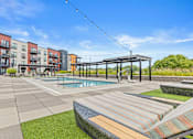 Thumbnail 22 of 36 - A pool area with a striped sun lounger and a building in the background.