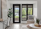 Thumbnail 7 of 36 - A modern living room with a black door and a view of a green lawn outside.