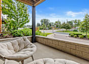 Thumbnail 8 of 36 - A patio with a cushioned chair and a table is overlooking a street.