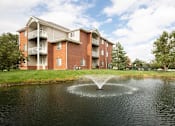 Thumbnail 27 of 33 - a fountain in the middle of a pond in front of an apartment building