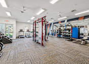Thumbnail 18 of 32 - A gym with a variety of equipment including a weight rack, treadmill, and exercise bench.