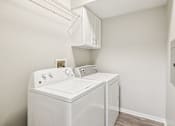 Thumbnail 13 of 32 - A white washing machine and dryer in a small laundry room.