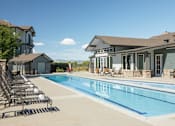 Thumbnail 20 of 20 - a swimming pool with chairs around it in front of a house