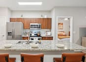 Thumbnail 2 of 53 - A kitchen with a granite countertop and brown chairs.