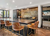 Thumbnail 18 of 53 - A modern kitchen with a bar area and chairs.