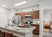 Thumbnail 10 of 40 - a kitchen with a granite counter top and a stainless steel refrigerator