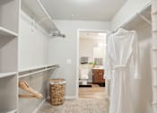 Thumbnail 28 of 40 - a walk in closet with a white robe and a bathroom
