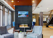 Thumbnail 8 of 27 - Lobby area with blue lounge chairs, floor to ceiling fireplace with mounted TV above