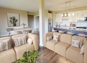 Thumbnail 7 of 27 - A living room with a couch and a dining area in the background.